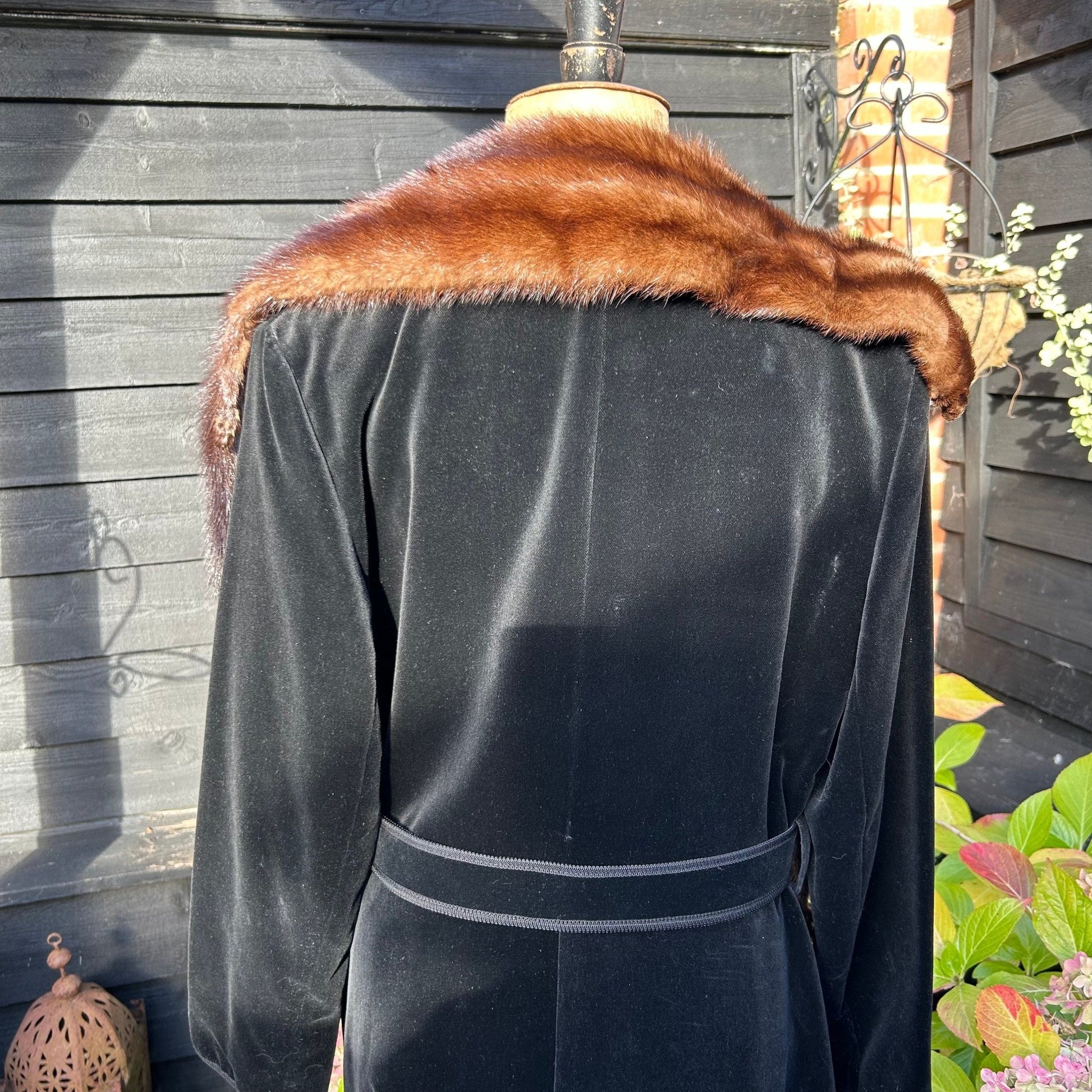 back view of Vintage mink fur stole around shoulders on black coat against black fence & greenery- Splendid Vintage World